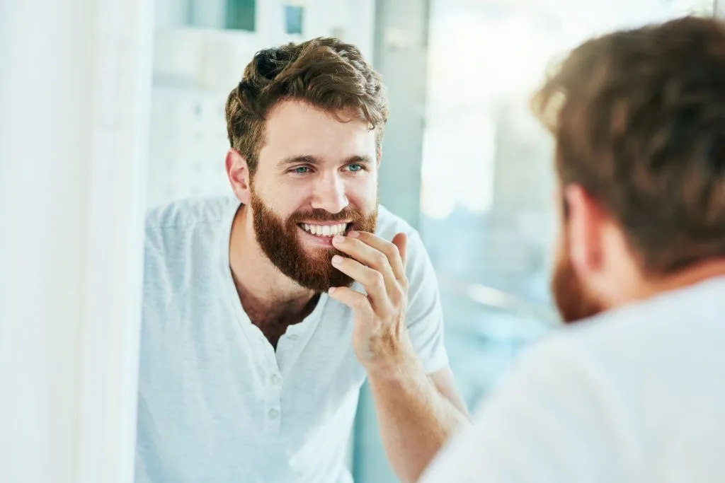 Bearded man smiling while looking at mirror